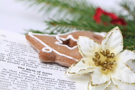 A Christmas cookie and flower on top of an open Bible.